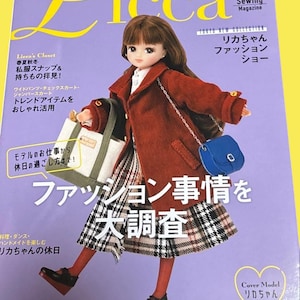 以下が含まれることがあります： 赤いコート、チェックのスカート、黒い靴を履いた人形が特徴の雑誌の表紙。雑誌のタイトルは「Licca」で、日本語のテキストが入っています。表紙にはファッションに関するテキストと「Cover Model」のラベルも含まれています。