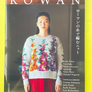 May include: A Rowan knitting pattern book featuring a light gray sweater with a colorful floral knit design on the front. The cover displays the text ROWAN, Japanese characters, and a list of contributors including Erika Tokai, Kazekobo, Mikiko Gasnier, Saichika, Sanae Nasu, Tomoko Noguchi, ARNE & CARLOS, Gemma Atkinson, Julia Frank, Kaffe Fassett, Lisa Richardson, and Martin Storey.
