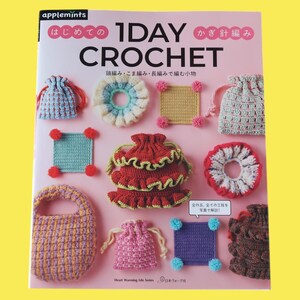 May include: A book cover featuring various crochet projects in a variety of colors, including bags, squares, and decorative elements. The title "1 Day Crochet" is prominently displayed, along with Japanese text and the "Heart Warming Life Series" logo.
