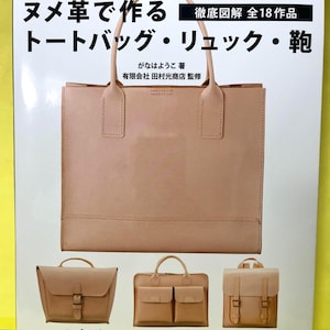 以下が含まれることがあります： 「Tanned Leather Hand-Made Bags」というタイトルの本で、表紙には大きなヌメ革のトートバッグが掲載されています。下部には3つの小さな革製バッグが並んでいます。表紙には日本語のテキストと、著者である「がなはようこ」の名前、および有限会社田村光商店監修の記載があります。
