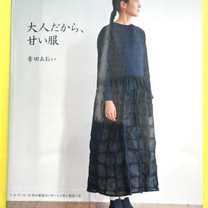 Peut inclure: Couverture de livre avec une femme portant une robe bleu foncé à manches longues et une jupe à motifs. Le titre du livre est "Vêtements doux pour adultes". Du texte japonais et le nom de l'auteur sont également visibles sur la couverture.