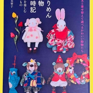 May include: A book cover with handmade fabric dolls in seasonal outfits. The dolls include a lamb, a rabbit, a bear, and a fish. Japanese text is visible on the cover.