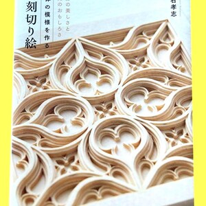 May include: A book cover featuring intricate, layered paper cut art in a light beige color. The design showcases a repeating pattern of stylized floral or gothic shapes. Japanese text is visible on the cover.