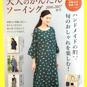 Könnte beinhalten: Das Cover eines japanischen Nähbuchs mit einer Frau in einem dunkelgrünen Kleid mit weißem Muster. Der Titel des Buches ist auf Japanisch, mit zusätzlichem Text und Bildern von Kleidung. Das Buch enthält Schnittmuster für Kleider, Oberteile und Tuniken.