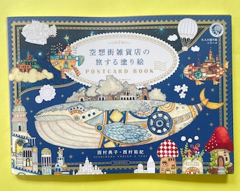 以下が含まれることがあります： 空想的なイラストが描かれたポストカードブック。表紙は青色で、クジラ、飛行船、建物が描かれています。「POSTCARD BOOK」と日本語の文字が書かれています。本には装飾的なボーダーがあります。