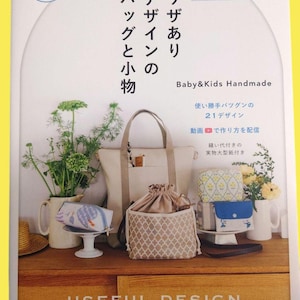 May include: A book cover with the title "Useful Design" featuring various handmade bags and small items. The cover includes text in Japanese and English, with a focus on baby and kids' handmade items.