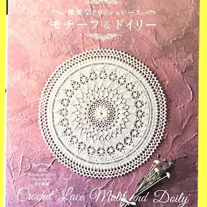 May include: A book cover featuring a white crochet doily on a pink background. The title "Crochet Lace Motifs and Doily" is displayed in cursive script. The book also includes Japanese text and measurements of 35cm and 52cm.
