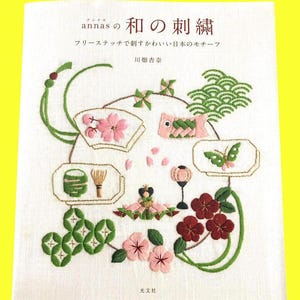 May include: A book cover featuring Japanese embroidery designs. The cover displays various embroidered motifs, including flowers, a carp streamer, and a butterfly, all in vibrant colors. The title is in Japanese characters, with the author's name and publisher's name also visible.