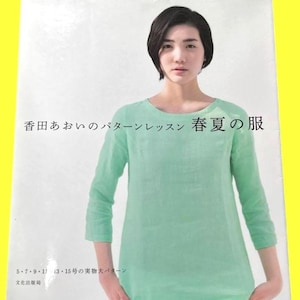 以下が含まれることがあります： 女性が明るい緑色の長袖シャツを着ている本の表紙。タイトルは日本語で、「春夏服」という言葉が見えます。表紙には日本語のテキストと黄色の背景も含まれています。