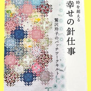 Könnte beinhalten: Buchcover mit einem farbenfrohen Patchwork-Design. Der Quilt besteht aus verschiedenen Stoffen mit Blumen- und anderen Mustern in Rosa, Blau und Grün. Japanischer Text ist auf dem Cover zu sehen, zusammen mit dem Titel "Happy Needlework".