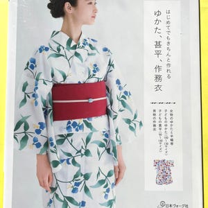 May include: A woman wearing a white yukata with a floral pattern of blue flowers and green leaves, tied with a red obi. The image is from a book with Japanese text, including "Yukata, Jinbei, Samue".