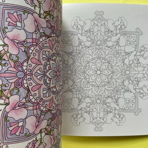 May include: A coloring book featuring two pages with intricate floral mandala designs. The left page is partially colored in shades of pink, purple, and lavender, while the right page displays the same detailed black and white line art pattern.