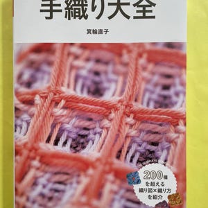 Peut inclure: Un livre japonais intitulé "Encyclopédie du tricot fait à la main" avec un motif tricoté coloré sur la couverture. Le livre présente du texte en japonais et détaille diverses techniques et motifs de tricot.