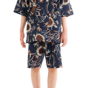 Könnte beinhalten: Marineblaues hawaiianisches Set aus Hemd und Shorts mit Blumen- und Palmenmuster. Das Set besteht aus einem kurzärmeligen Hemd und knielangen Shorts. Das Wort "hawaii" steht auf dem Stoff. Die Person trägt orangefarbene Flip-Flops.