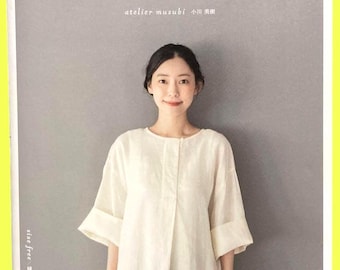 Può includere: Una copertina di libro che mostra una persona che indossa una camicetta color crema a maniche a tre quarti con pattina frontale e una gonna blu scuro. Il testo giapponese recita "ラフに着られる暮らしの服", "atelier musubi 小川美樹", "size free", "縫い代込みの実物大型紙つき" e "Heart Warming Life Series 日本ヴォーグ社".