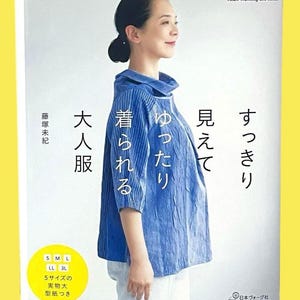 以下が含まれることがあります： Heart Warming Life Seriesと題された手芸本。ハイネックで七分袖の青いテクスチャーのあるトップスを着用した人物が写っている。表紙には日本語のテキストと、S、M、L、LL、3Lのサイズが記載された黄色い円形のバッジが含まれている。
