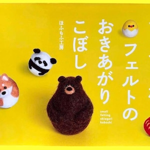 May include: A yellow book cover with Japanese text and felted animal figures. The cover features a panda, bear, Shiba Inu, chick, and Daruma doll. The title includes the words "small felting okiagari koboshi."