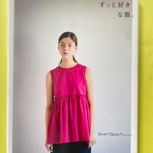 以下が含まれることがあります： 鮮やかなピンク色のノースリーブトップスを着た女性が表紙の書籍。表紙には日本語と英語の「Quoi? Quoi?」の文字が記載されています。背景は薄いグレーです。ファッションガイド。