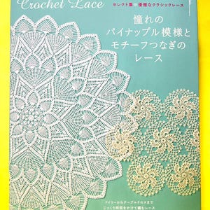 Könnte beinhalten: Ein blaugrünes Anleitungsbuch mit dem Titel Crochet Lace, das auf dem Einband weiße, komplizierte Ananas- und kreisförmige Spitzenmuster zeigt. Der Text enthält japanische Schriftzeichen sowie die englischen Wörter Crochet Lace.