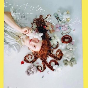 以下が含まれることがあります： 日本語のテキストと、ぬいぐるみで囲まれた女性の顔が描かれた本の表紙。本のタイトルは日本語です。女性は赤い髪を装飾的なカールでスタイリングしています。さまざまな小さなぬいぐるみがお互いの周りに散らばっています。