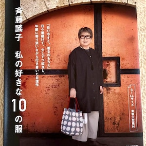 Könnte beinhalten: Buchcover mit japanischem Text und einer Frau in einem schwarzen Oberteil und grauer Hose, die eine Tragetasche mit weißem und blauem Polka-Dot-Muster hält. Der Buchtitel lautet "Saito Yokos 10 Lieblingskleider".