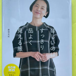 以下が含まれることがあります： Heart Warming Life Seriesと題された手芸本。黒と白のチェック柄のトップスを着た人物が表紙に写っている。表紙には日本語のタイトル、Sから3Lまでの5サイズ展開を示す黄色い円形のステッカー、日本ヴォーグ社のロゴが記載されている。