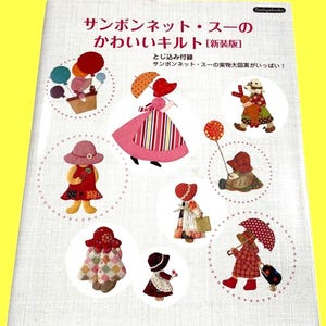 以下が含まれることがあります： 「サンボンネット・スーのかわいいキルト」というタイトルの本。白い表紙には、様々な衣装を着たサンボンネット・スーのキャラクターのイラストが描かれ、点線で囲まれています。背景は黄色です。
