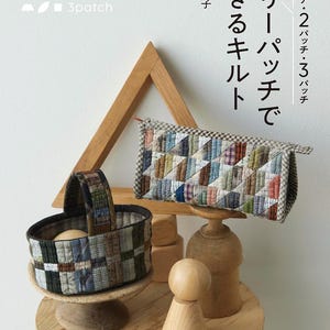 以下が含まれることがあります： パッチワークのデザインが施された、キルトバスケットと長方形のキルトポーチの静物画。本カバーの日本語テキストは「スリーブパッチ、キルトできます」と書かれています。木製の装飾要素も存在します。
