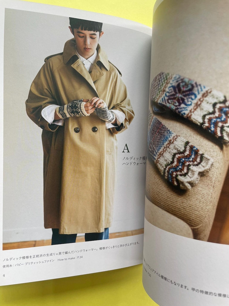 May include: A pair of fingerless knit gloves featuring a detailed Nordic-inspired pattern in cream, black, and blue. The gloves are shown being worn with a tan double-breasted trench coat and also displayed separately on a textured surface.