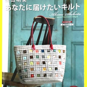 May include: A patchwork tote bag with red handles, resting on a wooden chair. The bag has a woven design with colourful squares. The book cover displays text in English and Japanese, including "Akemi Shibata Special Patchwork Designs".