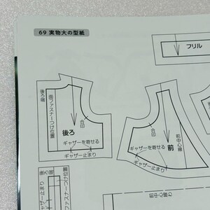 Op de afbeelding: Een pagina uit een naaipatronenboek met Japanse tekst. De pagina bevat diagrammen van kledingstukken, waaronder een voor- en achterpand, met labels en markeringen. De tekst bevat zinnen als "franje" en "verzamelen".