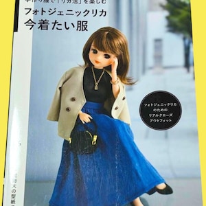 Op de afbeelding: Boekomslag met een pop in een zwarte top, blauwe rok en beige jasje. De boektitel is "Photogenic LiccA" in het Engels en Japans. De pop houdt een zwarte handtas vast en draagt zwarte schoenen.