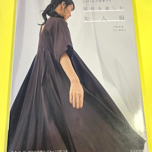 Op de afbeelding: Boekomslag met een vrouw in een donkerbruine jurk. De Japanse titel vertaalt naar "Genieten van individualiteit, kleding voor volwassenen". De omslag bevat ook de namen van de auteurs en de patroonmaten.