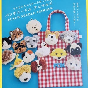 以下が含まれることがあります： 英語と日本語で「PUNCH NEEDLE ANIMALS」と書かれた青い本の表紙。犬、猫、キツネなど、さまざまなふわふわの動物のデザインが、赤と白のチェック柄のトートバッグに付いています。