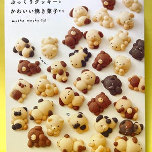 May include: A collection of bear-shaped cookies in various shades of brown and beige, arranged on a white surface. Some cookies have dark brown accents, while others are plain. The text "mocha mocha" and Japanese characters are visible.