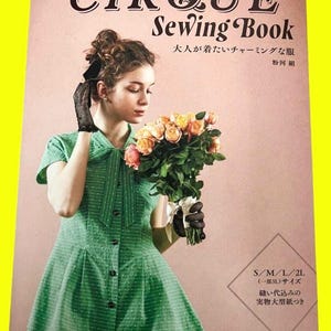 以下が含まれることがあります： バラの花束を持つ女性が特徴のヴィンテージ裁縫本「CIRQUE Sewing Book」。表紙には英語と日本語のテキストがあります。女性は白い水玉模様の緑色のドレスと黒い手袋を着用しています。