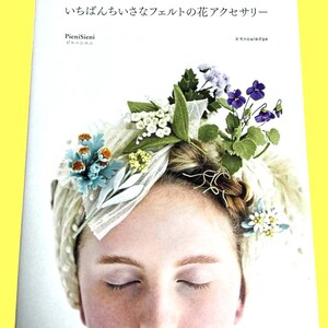 May include: A book cover featuring a woman wearing a floral headpiece. The headpiece includes blue, white, and purple flowers with green leaves. The book title is in Japanese, with the author's name and publisher also visible.