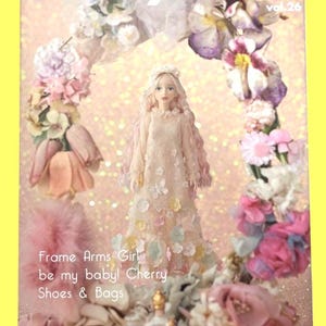 May include: A magazine cover with the title "Dollybird vol. 26" features a doll in a pink dress surrounded by flowers. The text "Frame Arms Girl be my baby! Cherry Shoes & Bags" is also visible. The background is a light pink with glitter.