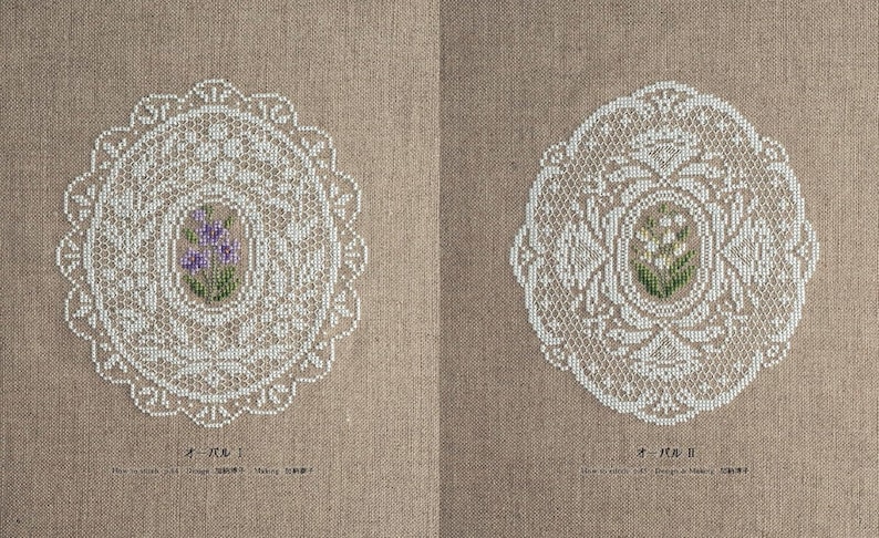 Op de afbeelding: Twee gedetailleerde witte kanten doilies met bloemmotieven in het midden, op een beige stoffen achtergrond. E&eacute;n doily heeft paarse bloemen, de andere witte. De ovale doilies hebben ingewikkelde patronen.