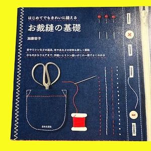 以下が含まれることがあります： 青色の本の表紙。日本語のテキストと、裁縫道具と技術のイラストが描かれています。表紙には、ハサミ、針と糸、赤い糸巻きが描かれています。本のタイトルは「裁縫の基礎」です。