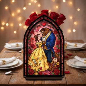 Può includere: Un pannello decorativo in stile vetrata raffigurante Belle e la Bestia de La Bella e la Bestia. Il pannello è ambientato su uno sfondo di rose rosse e luci soffuse. I personaggi sono nei loro abiti classici, circondati da rose e cuori.