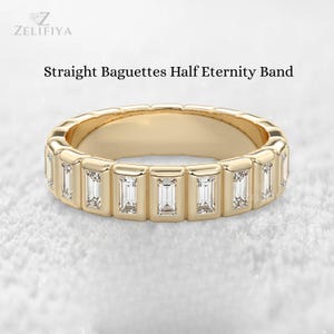 May include: A gold-colored ring with a half-eternity band design. The ring features rectangular-cut, clear gemstones set in a channel setting. The text "Straight Baguettes Half Eternity Band" is displayed above the ring.