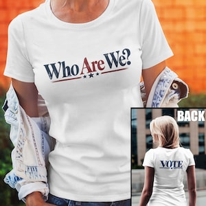 May include: A white short-sleeved t-shirt featuring the text Who Are We? in dark blue and red lettering on the front, with three small stars underneath. The back of the shirt displays the word VOTE in dark blue text with a single star underneath.
