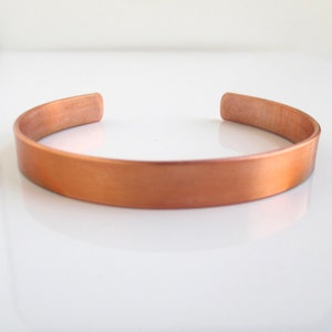 May include: A simple copper cuff bracelet with a brushed finish.