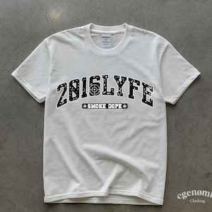 May include: White t-shirt with a crew neck and short sleeves. The front displays the text "2016LYFE" in a black, collegiate-style font, with a target graphic in the center. Below the text is "SMOKE DOPE" with cannabis leaf accents.