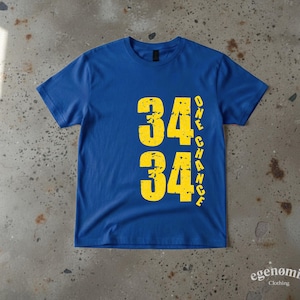 Op de afbeelding: Een koningsblauw T-shirt met korte mouwen en een verweerde gele afbeelding op de voorkant. Het ontwerp toont het getal 34 twee keer verticaal gestapeld, met de tekst ONE CHANCE verticaal in gele hoofdletters aan de rechterkant.