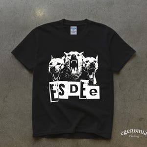 Op de afbeelding: Zwart T-shirt met een witte afbeelding van drie grommende honden. De tekst "ESDe" is onder de honden gedrukt in een blokletterstijl. Het shirt is gemaakt van een zacht materiaal.