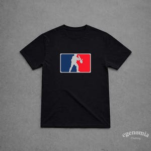 Könnte beinhalten: Schwarzes T-Shirt mit einer weißen und grauen Silhouette einer Person, die ein Musikinstrument in einem roten, weißen und blauen Rechteck hält. Das T-Shirt hat kurze Ärmel und einen Rundhalsausschnitt. Der Markenname "egenomia clothing" ist unten rechts in Weiß aufgedruckt.