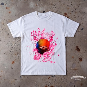 May include: A white short-sleeve t-shirt featuring a central graphic of a circular gradient sun with a detailed eye at its center. The design includes pink crystal shapes, swirling smoke-like elements, and the text HALF BLOOD in pink lettering.