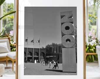 May include: A black and white photograph of the St. Louis Zoo entrance with the iconic "Zoo" sign in the foreground. The sign is made of large, stacked concrete letters. People are walking in the background.